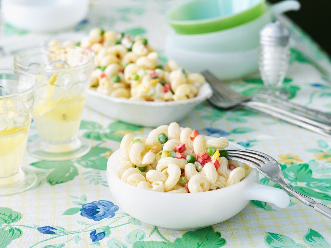 Bowl of Pasta Salad on Tabled with Serving Bowl and Drinks