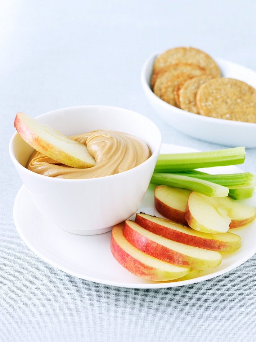 Kleiner Snack mit Erdnussbutter-Dip, Apfelspalten und Stangensellerie