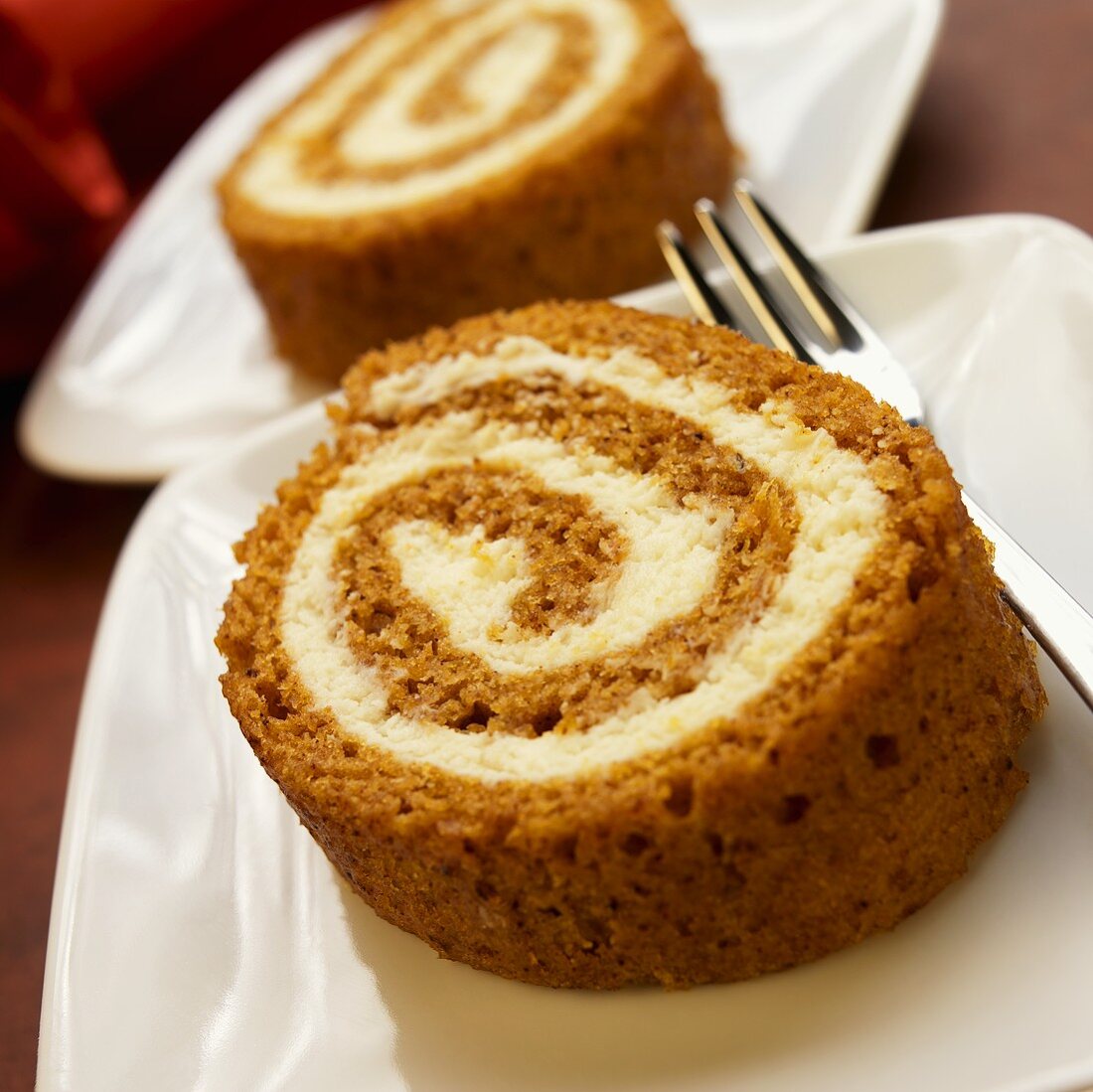 Two Slices of Pumpkin Spice Roll on White Plates; Fork