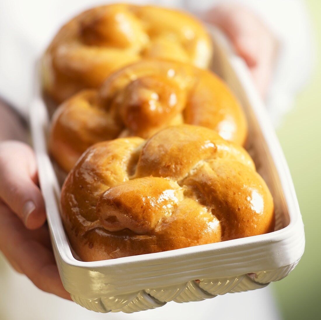 Hands Holding Ceramic Basket with Challah Rolls