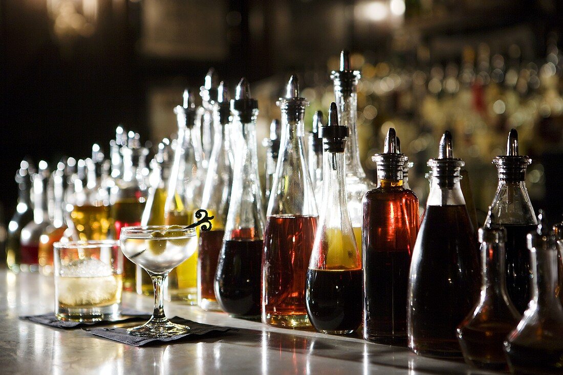 Barstilleben mit Cocktails und vielen Spirituosenflaschen