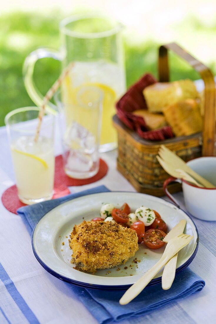 Picknick mit paniertem Hähnchen, Tomaten-Mozzarella-Salat und Limonade