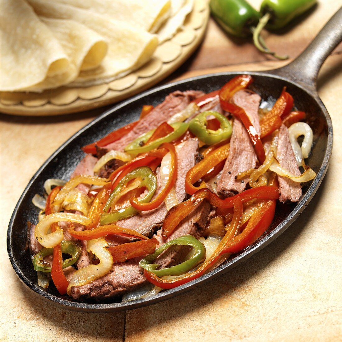 Rindfleisch mit Paprika und Zwiebeln in Pfanne, Tortillas (Mexiko)