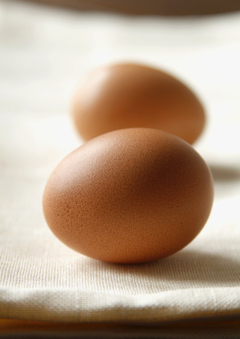 Zwei braune Eier auf weißem Leinentuch