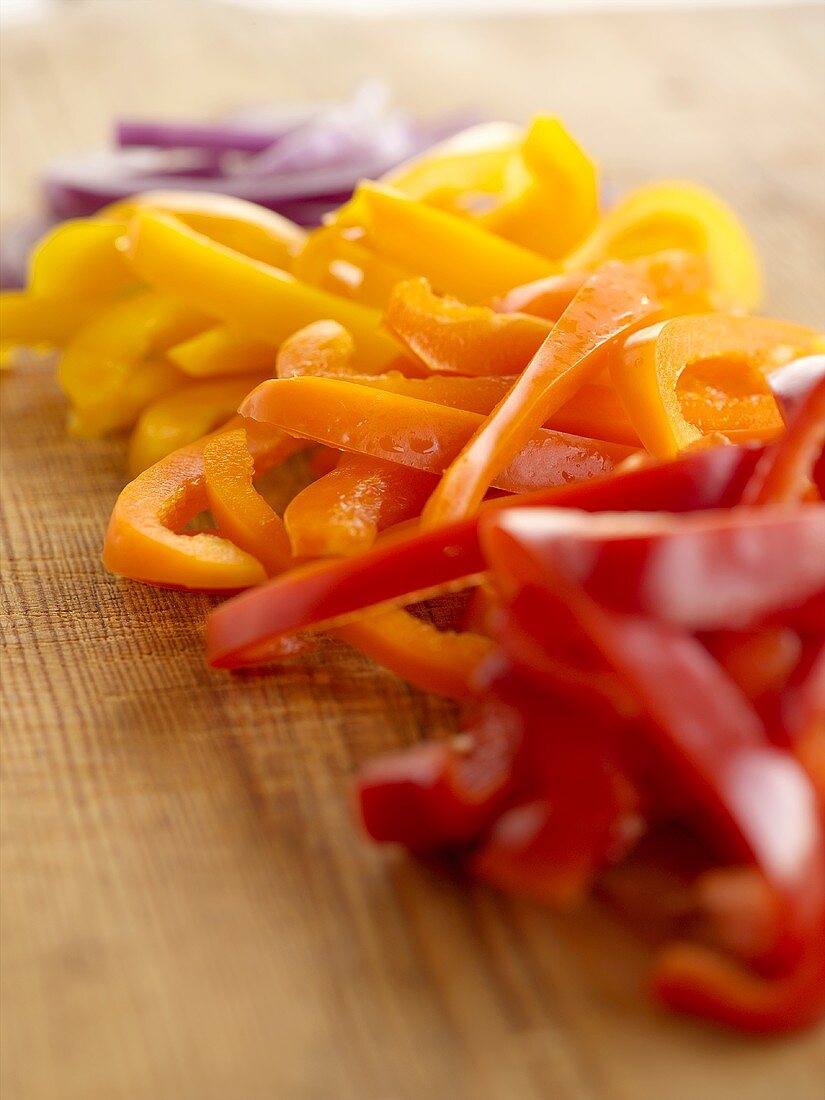 Sliced Multi-Colored Bell Peppers with Onions on Cutting Board