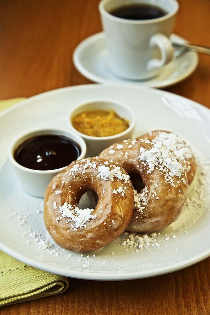 Donuts mit Zuckerglasur, Dips und einer Tasse Kaffee