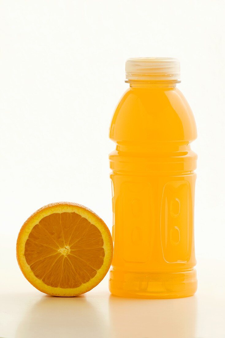 Fitnessdrink in Plastikflasche neben halber Orange