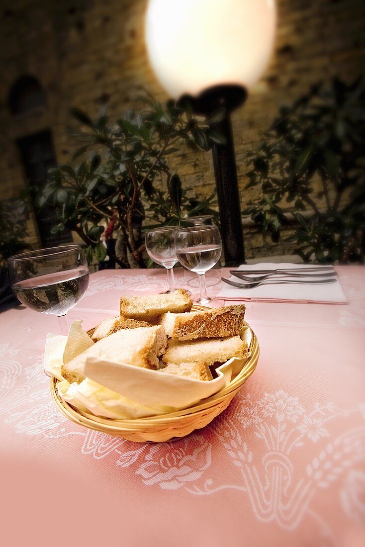 Weißbrot im Brotkorb und Weingläser auf Tisch (Italien)