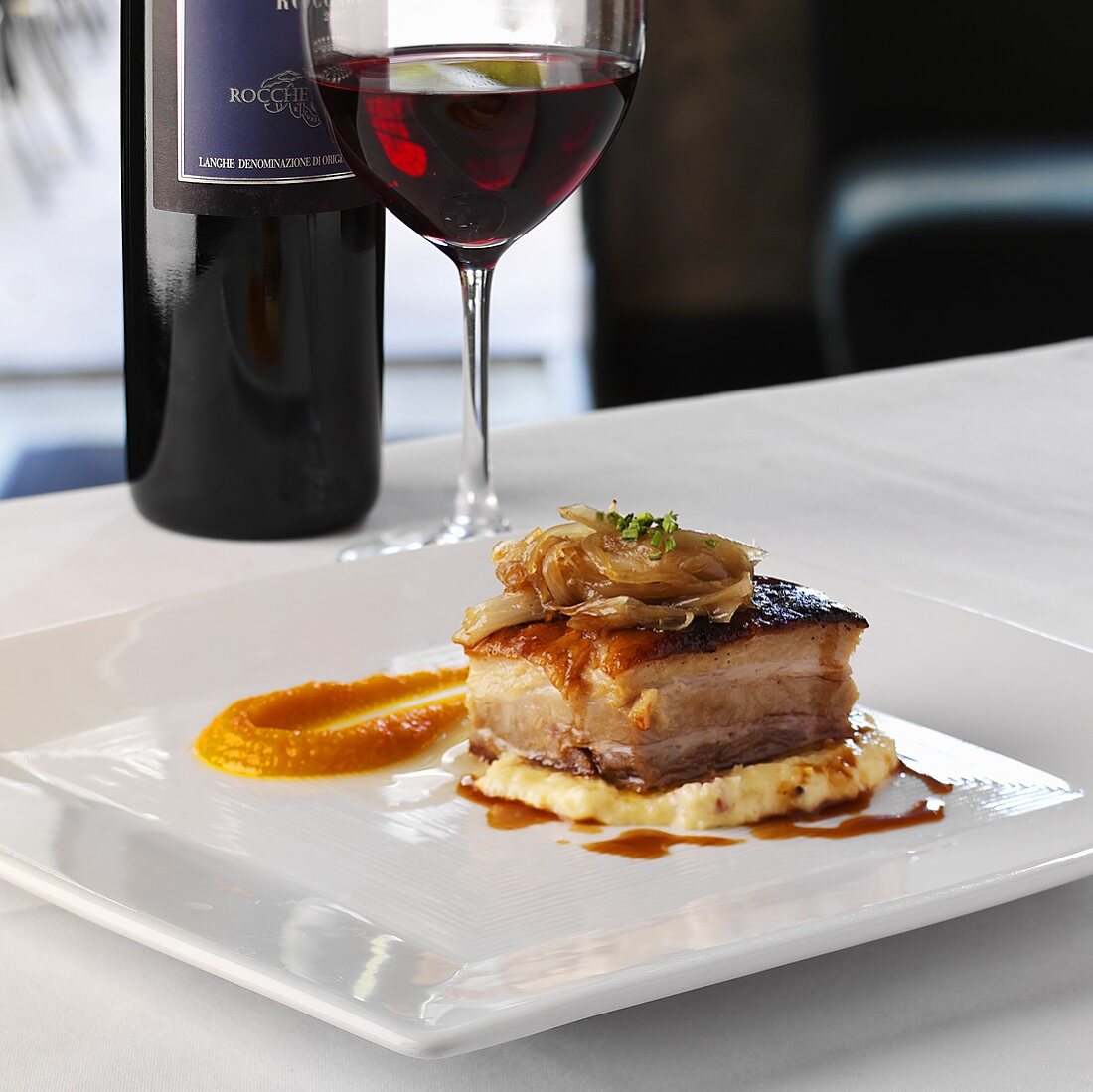 Beer-braised pork belly on polenta with caramelised shallots and carrot coulis