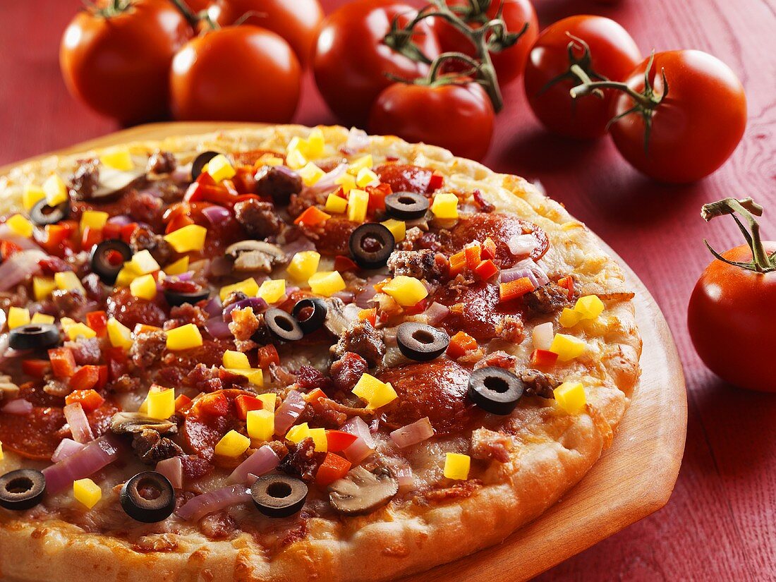 Pizza mit Peperoniwurst, Pilzen, Oliven und Paprikawürfeln