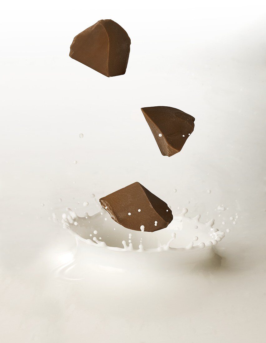 Schokoladenstücke fallen in Milch