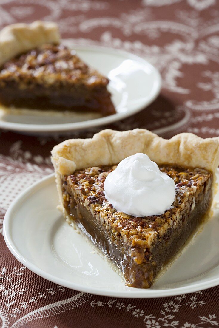Two pieces of pecan pie with cream