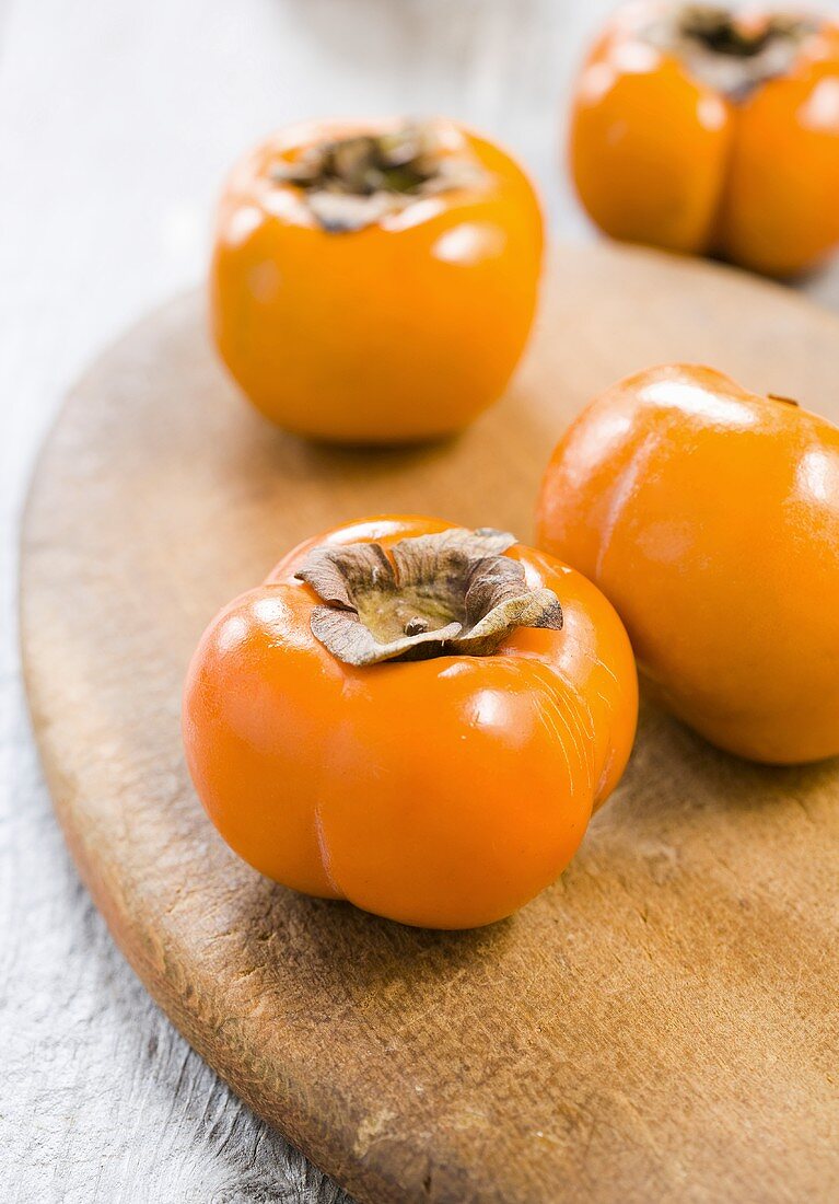 Several persimmons on chopping board