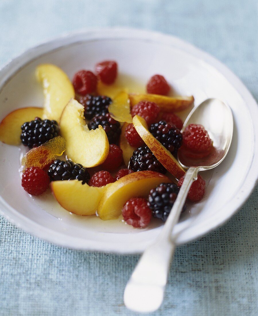 Pfirsich-Beeren-Salat in Schale mit Löffel