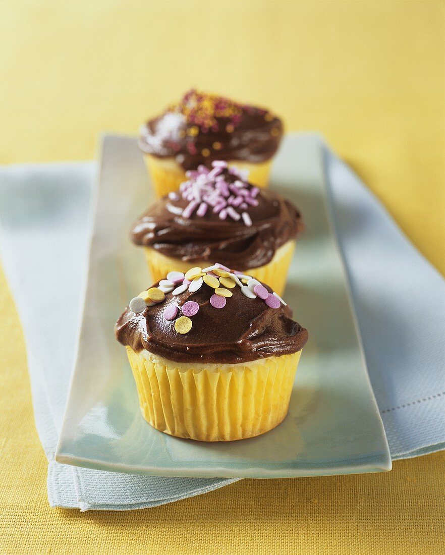 Yellow Cupcakes with Chocolate Frosting and Colored Sprinkles