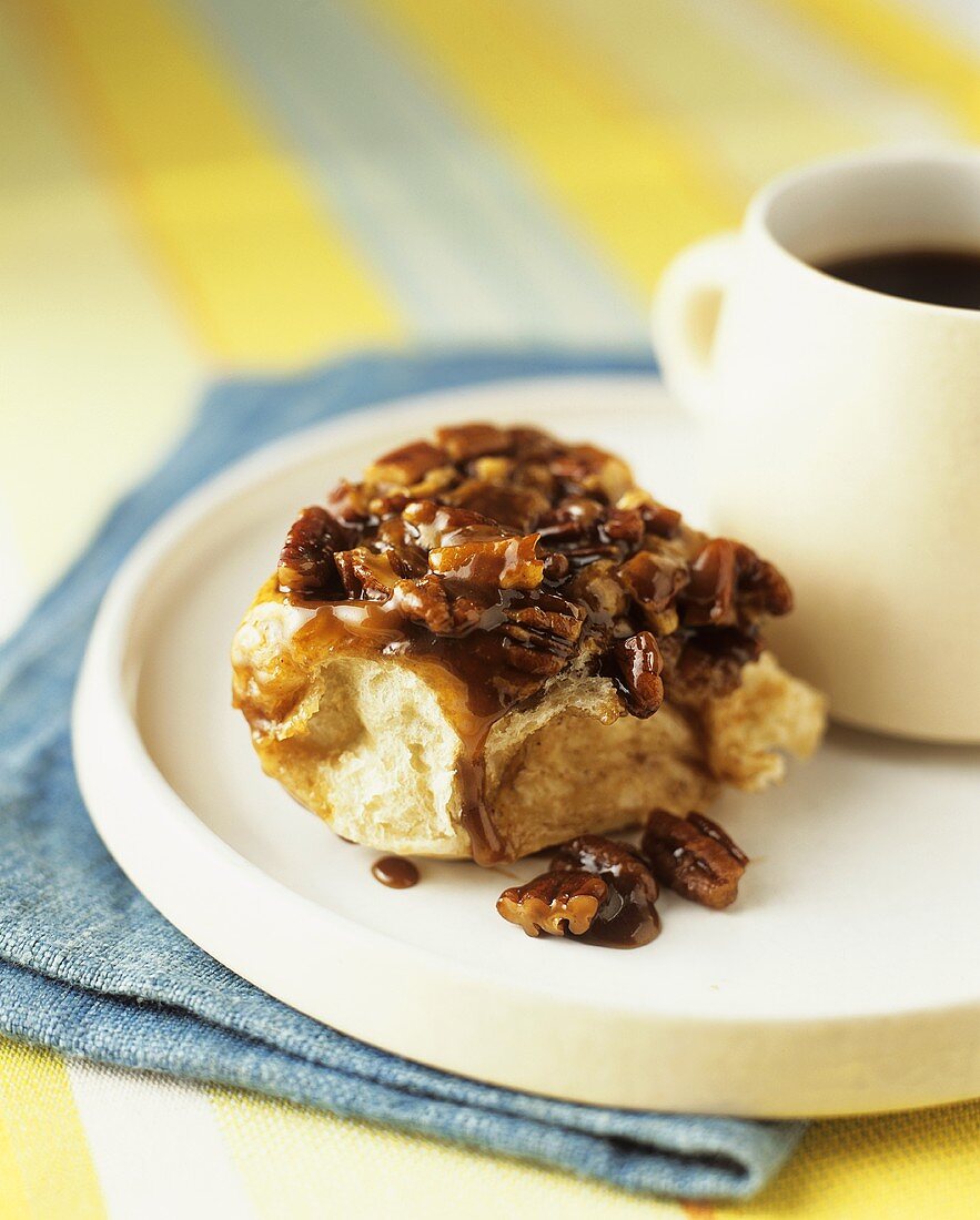 Sticky bun with caramel sauce and pecans, served with coffee (USA)