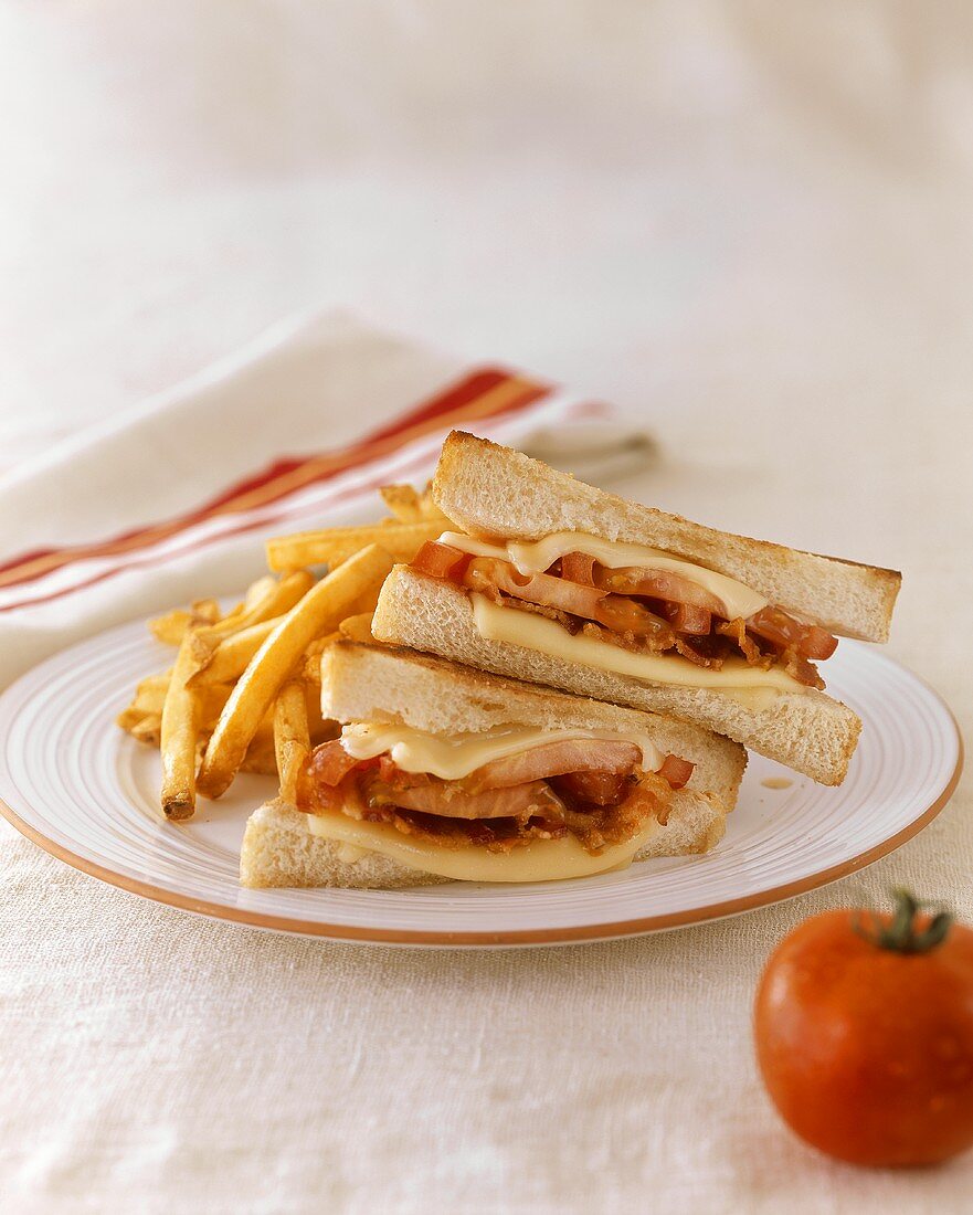 Getoastete Sandwiches mit Bacon, Tomaten, Käse und Pommes frites