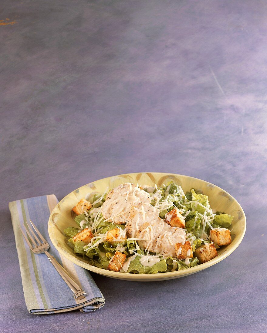 Chicken Caesar Salad in a Bowl; Cloth Napkin and Fork