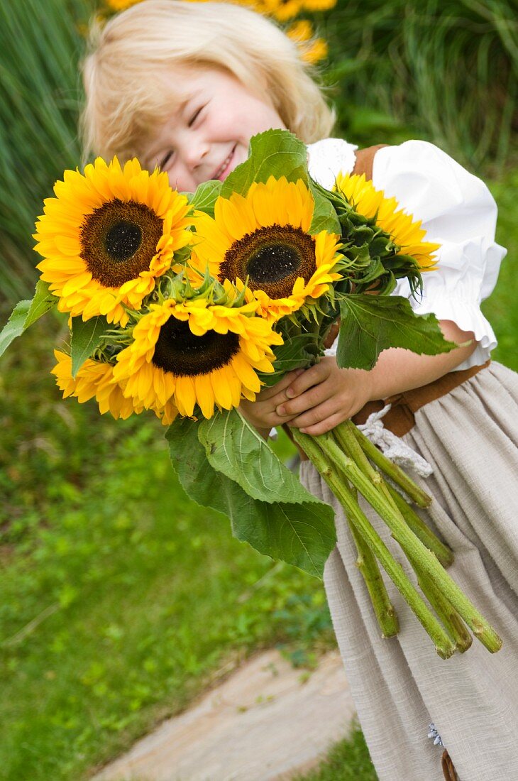 Mädchen hält Blumenstrauss mit Sonnenblumen
