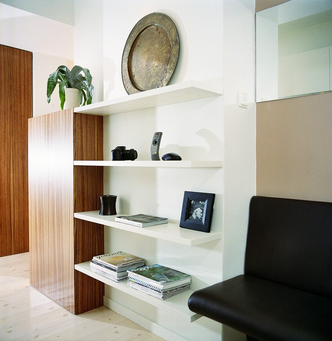 Various objects on a wall shelf next to a leather-covered bench