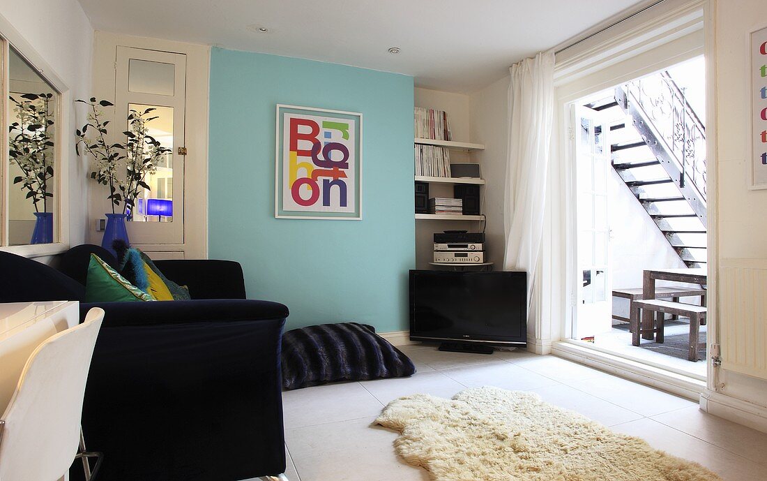 A living room with a sofa, floor cushions and a window