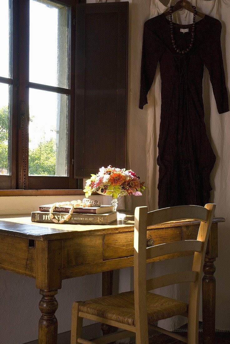 Ein rustikaler Holzschreibtisch mit Stuhl vor dem Fenster