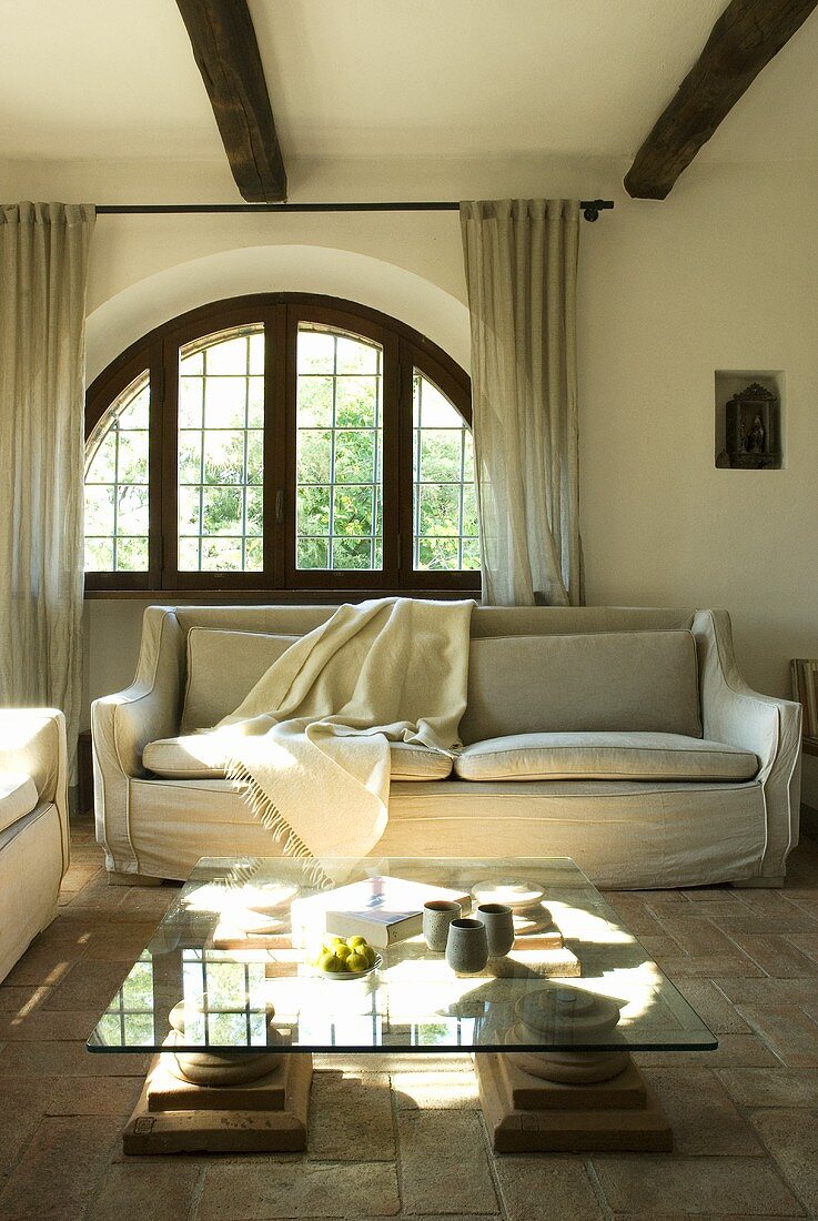Ein niedriger Wohnzimmertisch mit Glasplatte vor einem Sofa