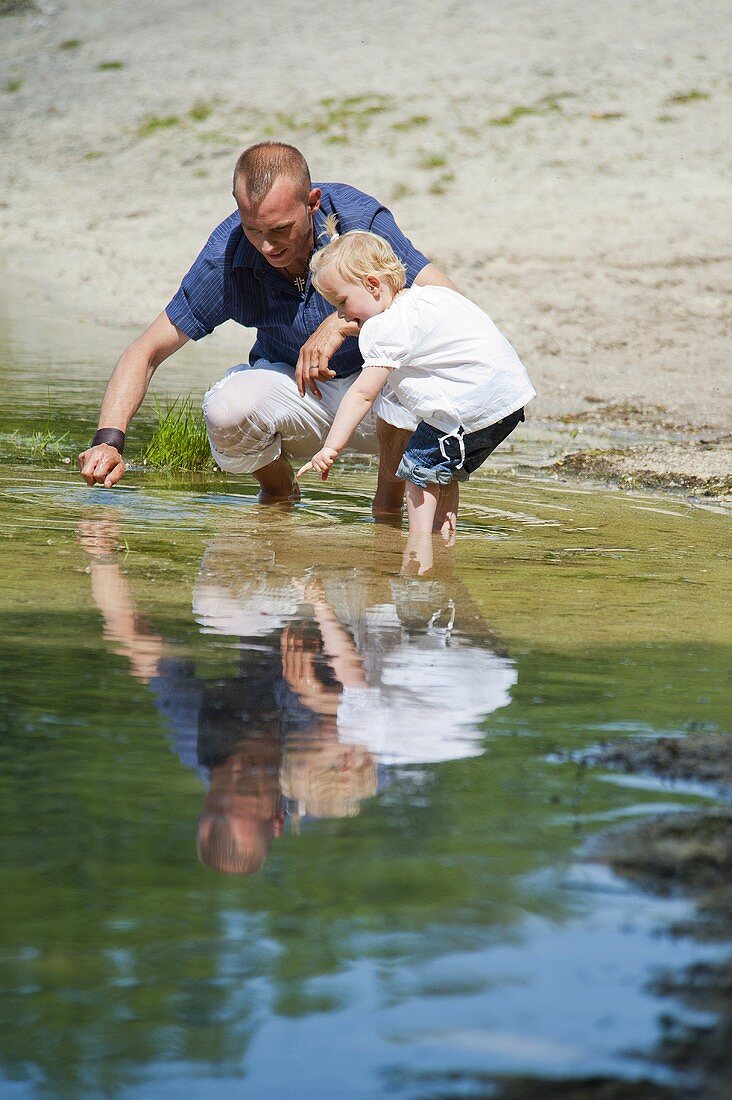 Vater und kleine Tochter spielen im See