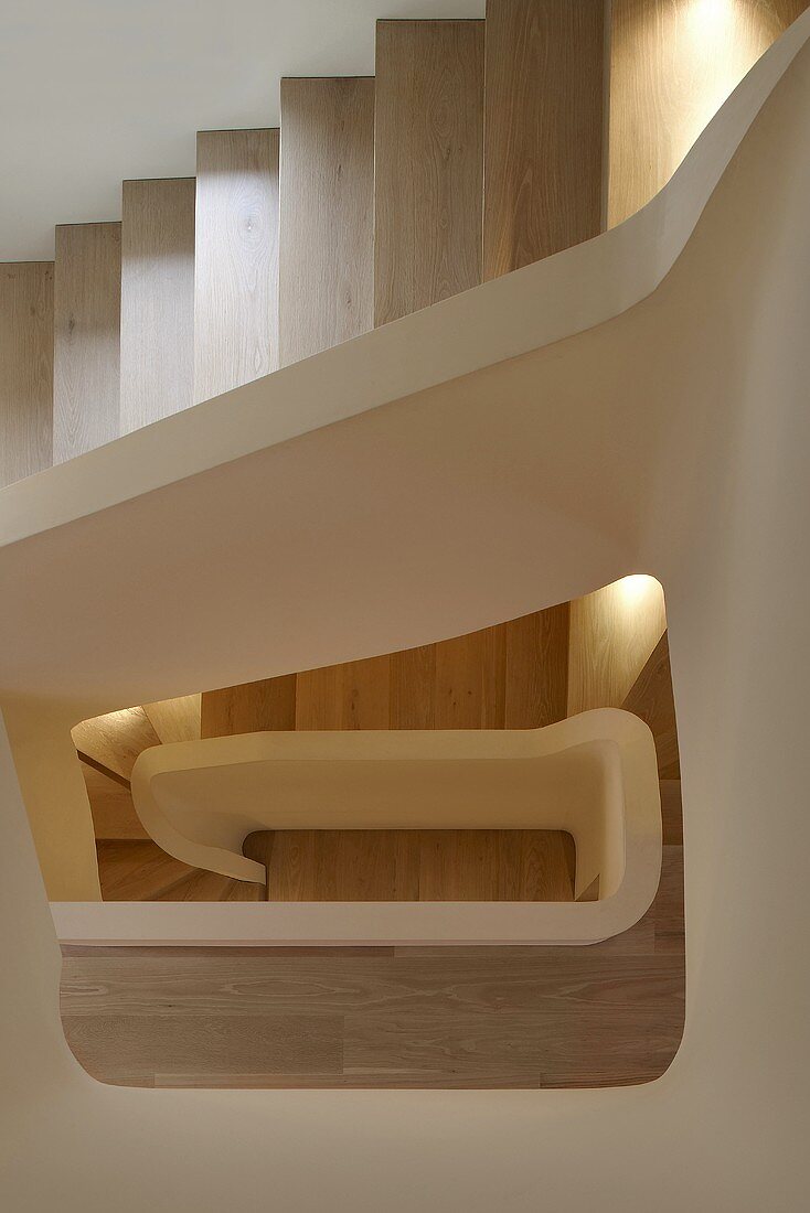 Of view through the stairwell of a modern multi-storey house with wooden steps