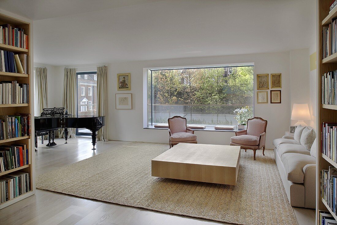 Open modern living room with a square wooden coffee table in front of upholstered armchairs in rococo style