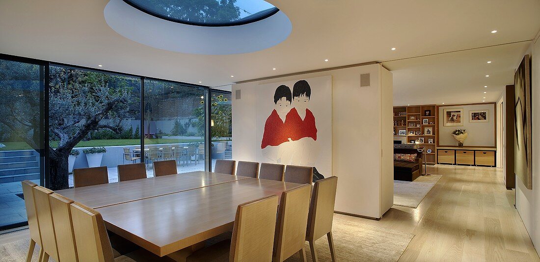 Dusk falling on a modern, newly built house with a dining table under a circular skylight in an open plan living area