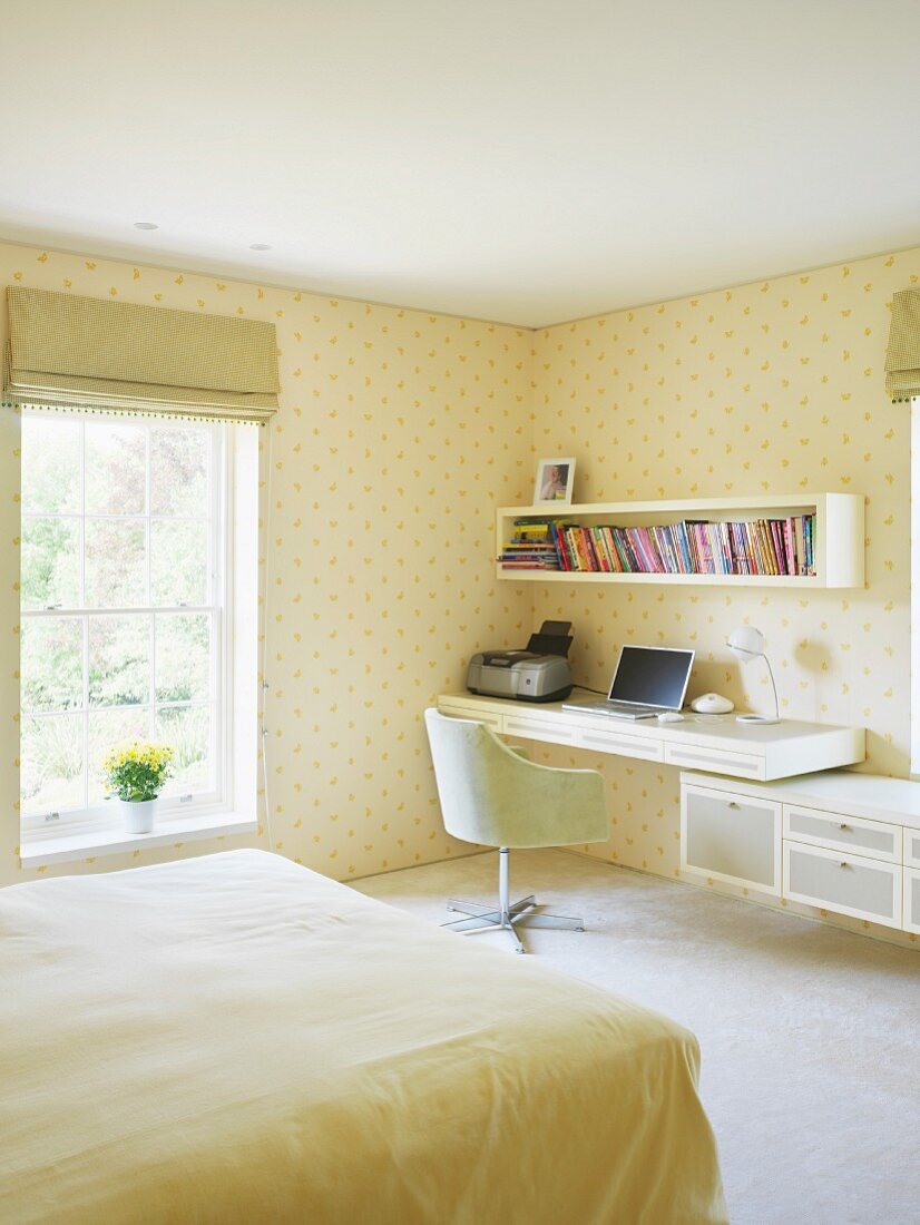 Bright bedroom with a home office in the corner and yellow patterned wallpaper on the wall