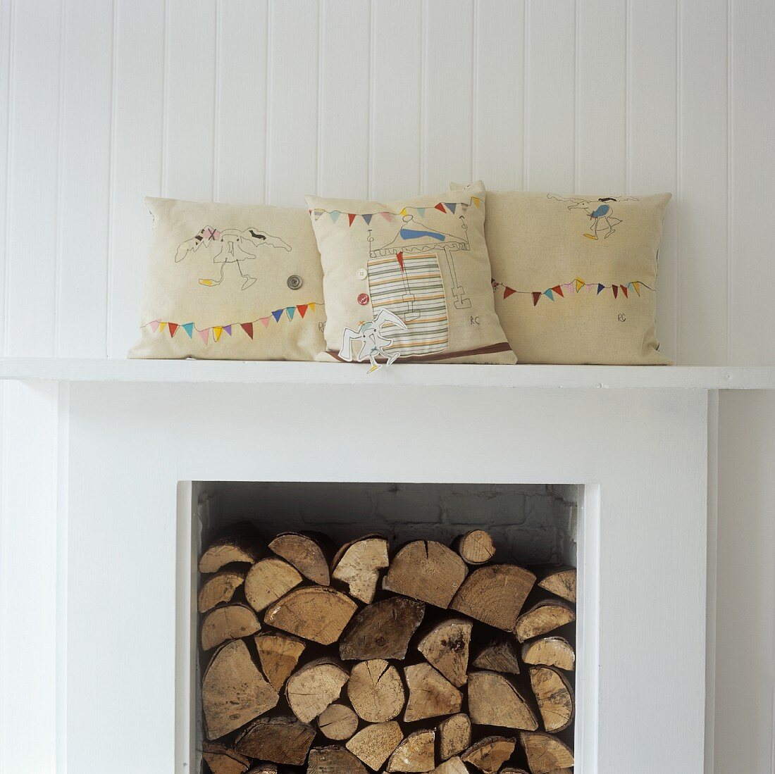 Firewood in a fireplace and decorative pillows on the mantelpiece