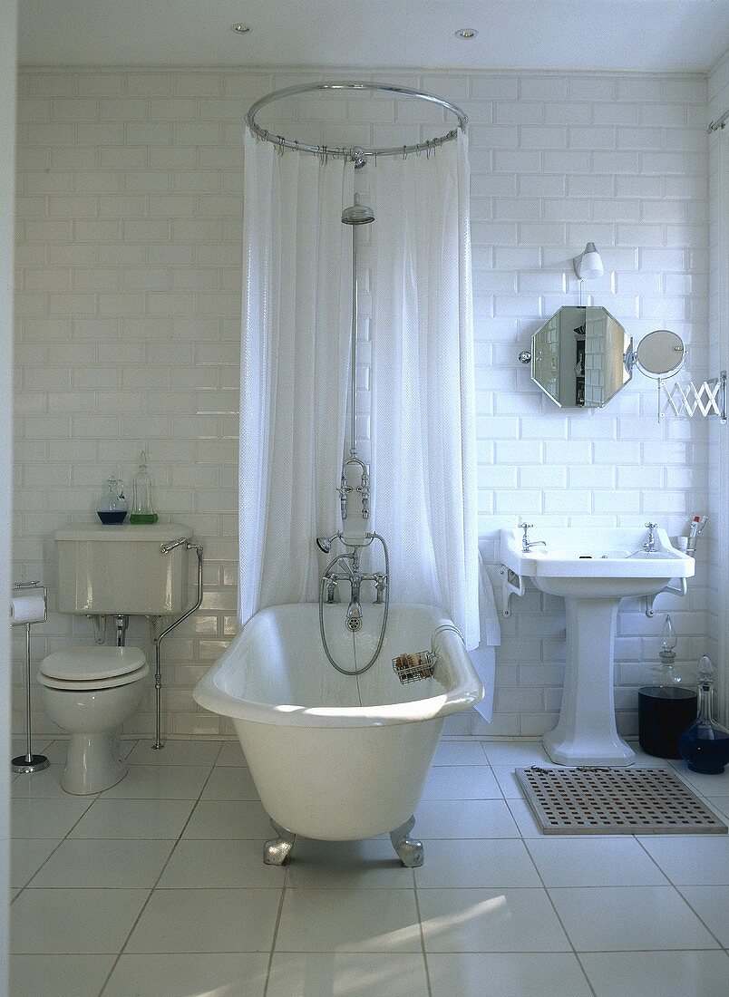Traditional, white tiled bathroom with a free standing roll top bathtub, chrome.