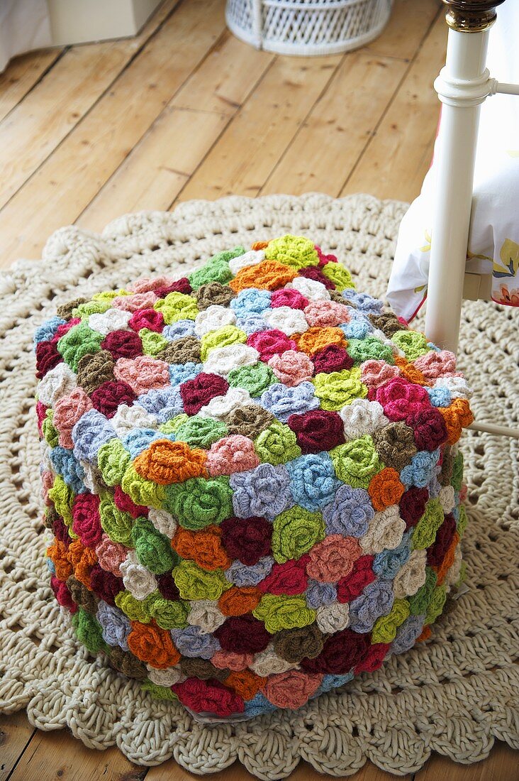 A stool made of colourful crocheted flowers on a crocheted rug