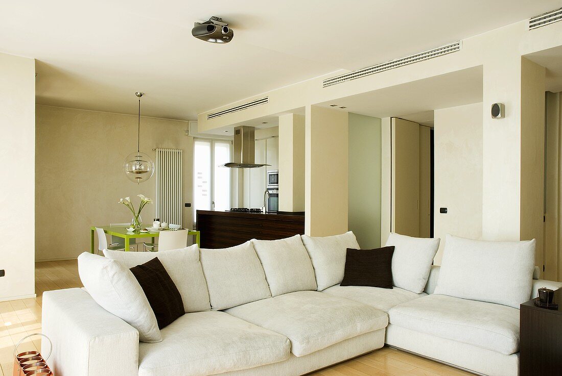 A white corner sofa with brown cushions in an open living-room-cum-dining-room