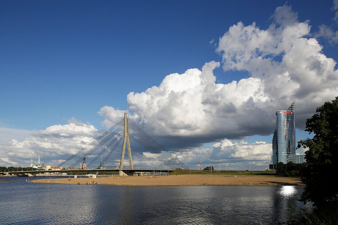 Badestrand in Kipsala unter der Vansu Tilts Bruecke, rechts The Sun Stone (Bueroturm der Svedbank), Fluss Daugava, hinten die Altstadt, Blick aus Kipsala, Riga, Lettland