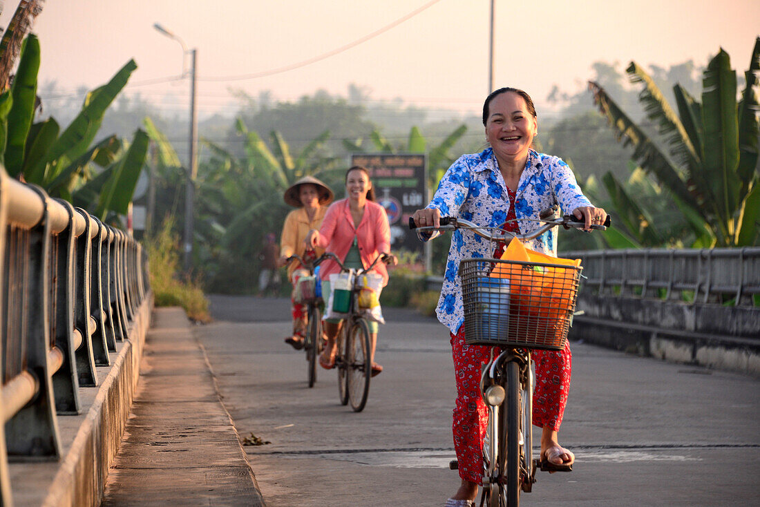 Locals cycling, in An Binh in the delta of Mekong river, Vietnam, Asia