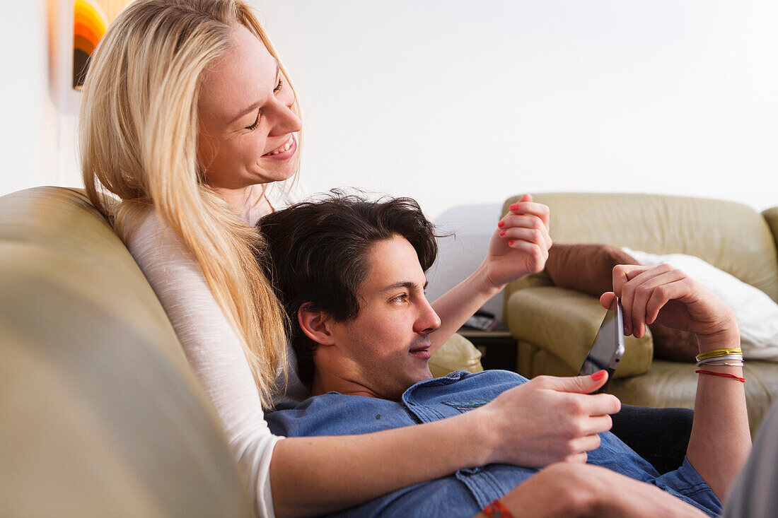 Junges Paar entspannt sich auf dem Sofa, Spielt auf dem Tablet