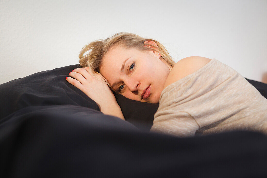 Junge Frau entspannt sich auf dem Sofa, Nachdenklich