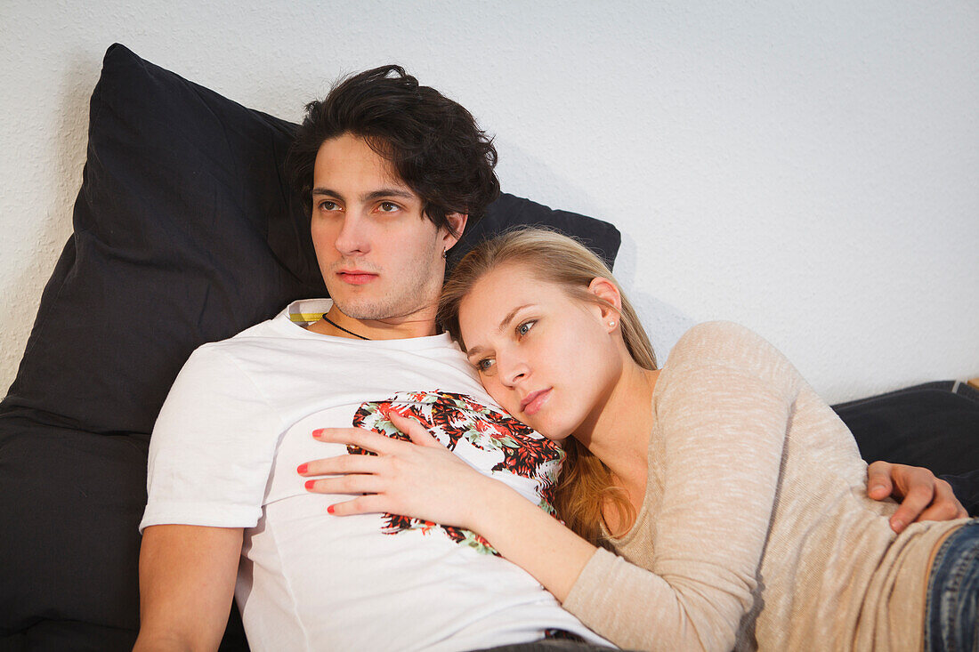 Young couple relaxing on the sofa, Hugging, Pensive