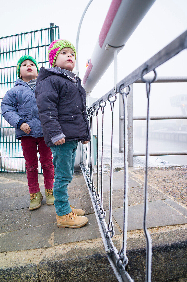Boys looking over a level-crossing, Cuxhaven, North Sea, Lower Saxony, Germany