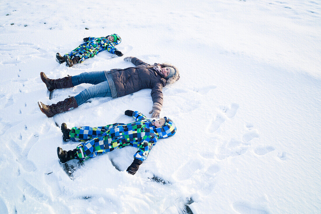 Mother and sons playing in the snow, Cuxhaven, North Sea, Lower Saxony, Germany