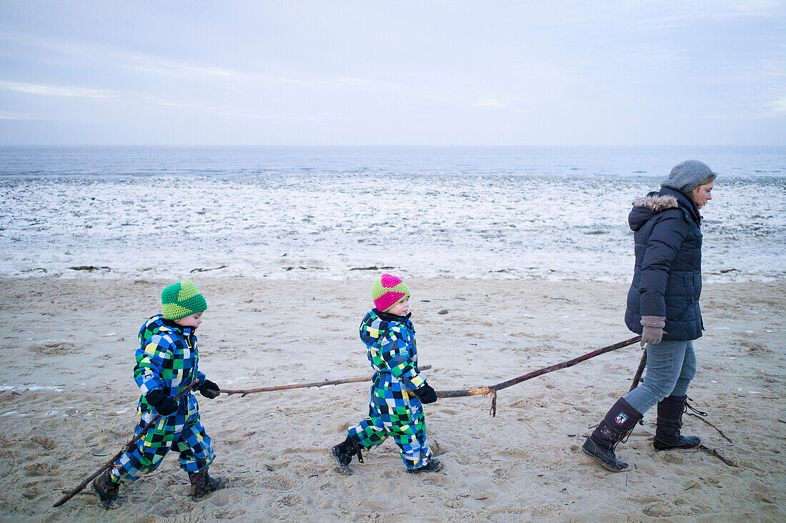 Young mother walking with her sons on the beach, Cuxhaven, North Sea, Lower Saxony, Germany