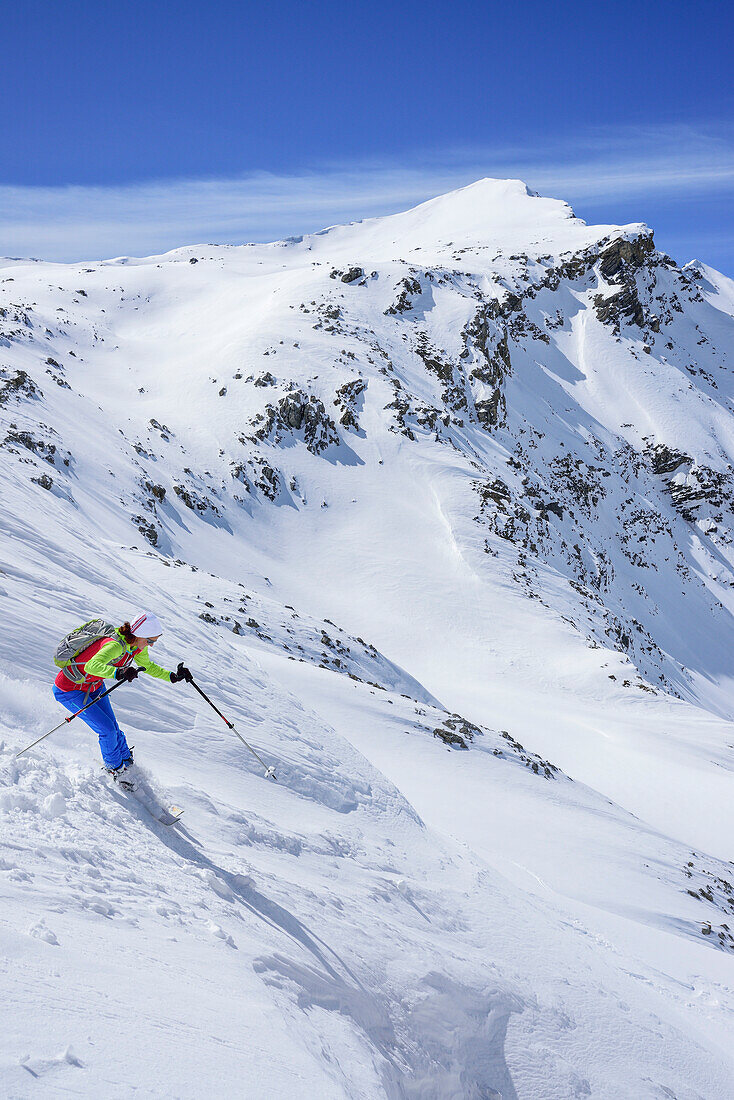 Woman back-country skiing downhill from Piz Uter, Piz Uter, Livigno Alps, Engadin, Grisons, Switzerland