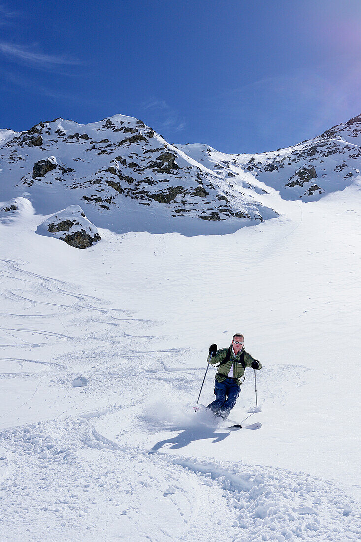 Man back-country skiing downhill from Piz Uter, Piz Uter, Livigno Alps, Engadin, Grisons, Switzerland