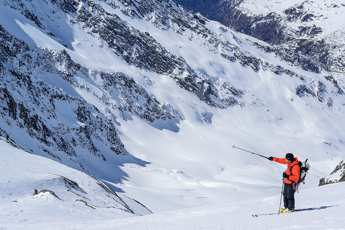Man back-country skiing pointing towards glacier, Dreiherrnspitze, valley of Ahrntal, Hohe Tauern range, South Tyrol, Italy