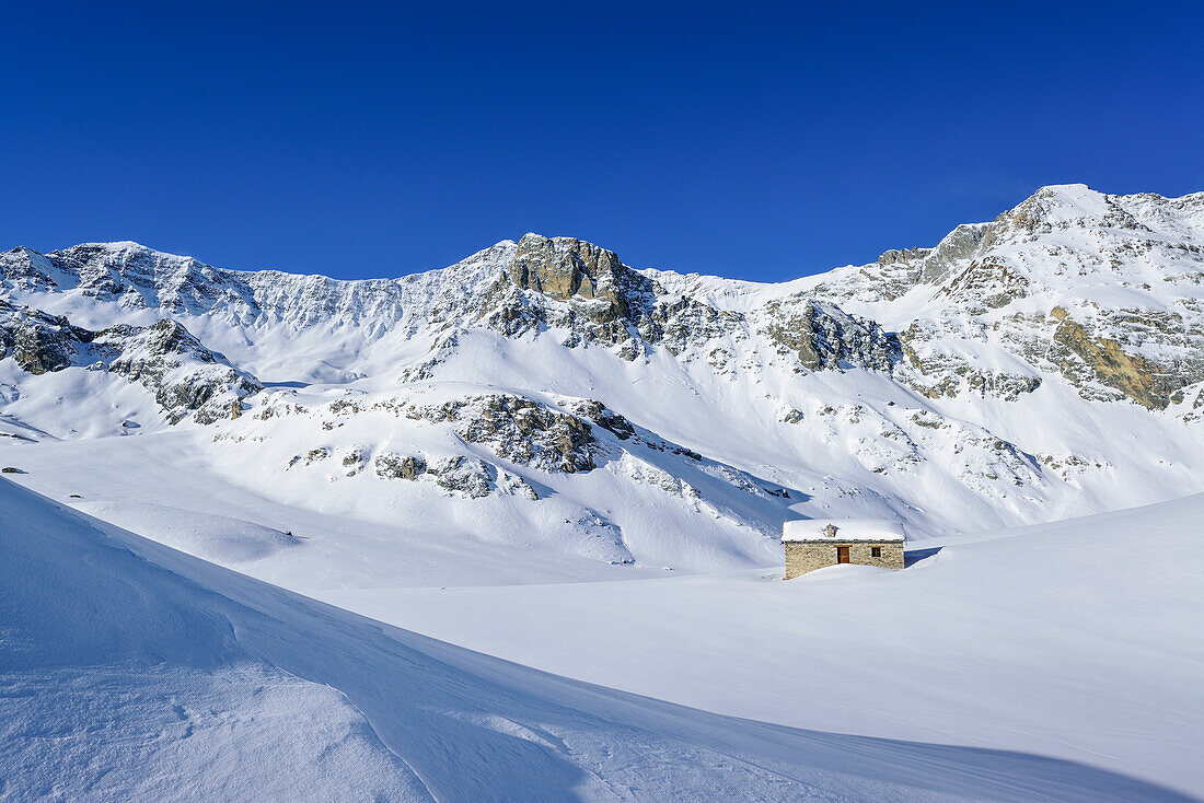 Snow covered alpine hut with Monte Reghetta, Monte Faraut and Monte Gabel, Rocca La Marchisa, Valle Varaita, Cottian Alps, Piedmont, Italy