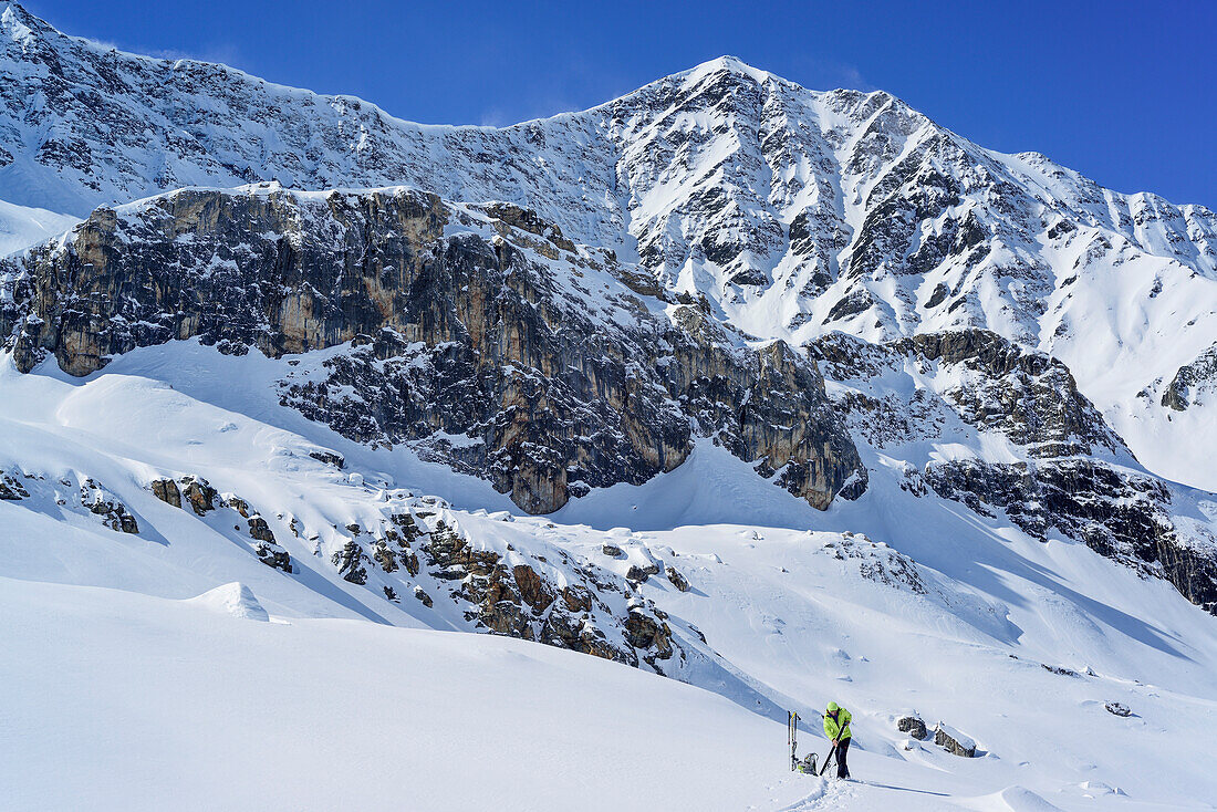 Frau auf Skitour zieht Felle auf, Colle di Vers, Valle Varaita, Cottische Alpen, Piemont, Italien