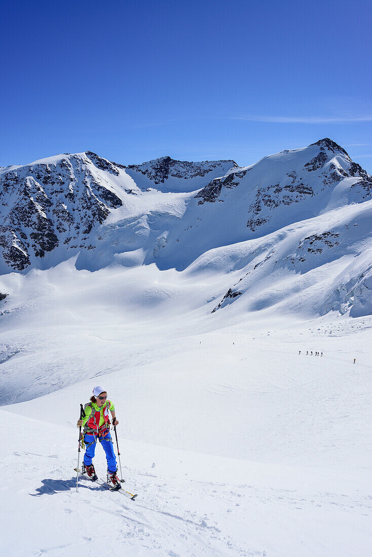 Woman back-country skiing ascending towards Punta San Matteo, Punta Taviela and Punta Cadini in background, Punta San Matteo, Val dei Forni, Ortler range, Lombardy, Italy